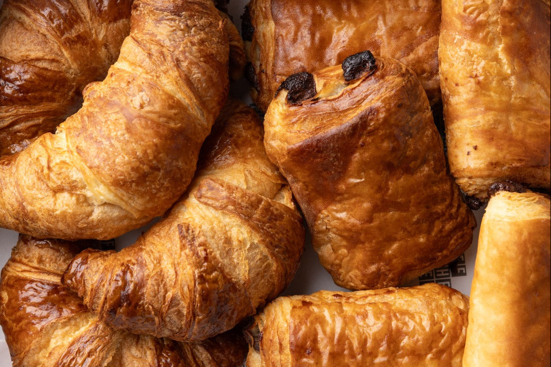 Close-up of various pastries including croissants and buns on a white surface.